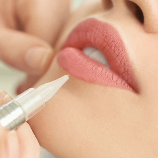 Ein Lippenpflegeprodukt wird mit einem feinen Stift auf die Lippen aufgetragen.